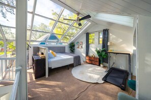 A room with a skylight, a bed, a desk, and a small plant. - Treehouse - Sleeps 14, Hot Tub, 2-Story Solarium (Sioux Falls)