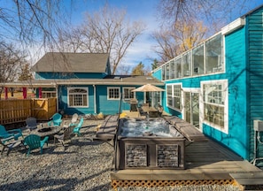 A backyard with a hot tub, outdoor seating, and a wooden deck. - Treehouse - Sleeps 14, Hot Tub, 2-Story Solarium (Sioux Falls)