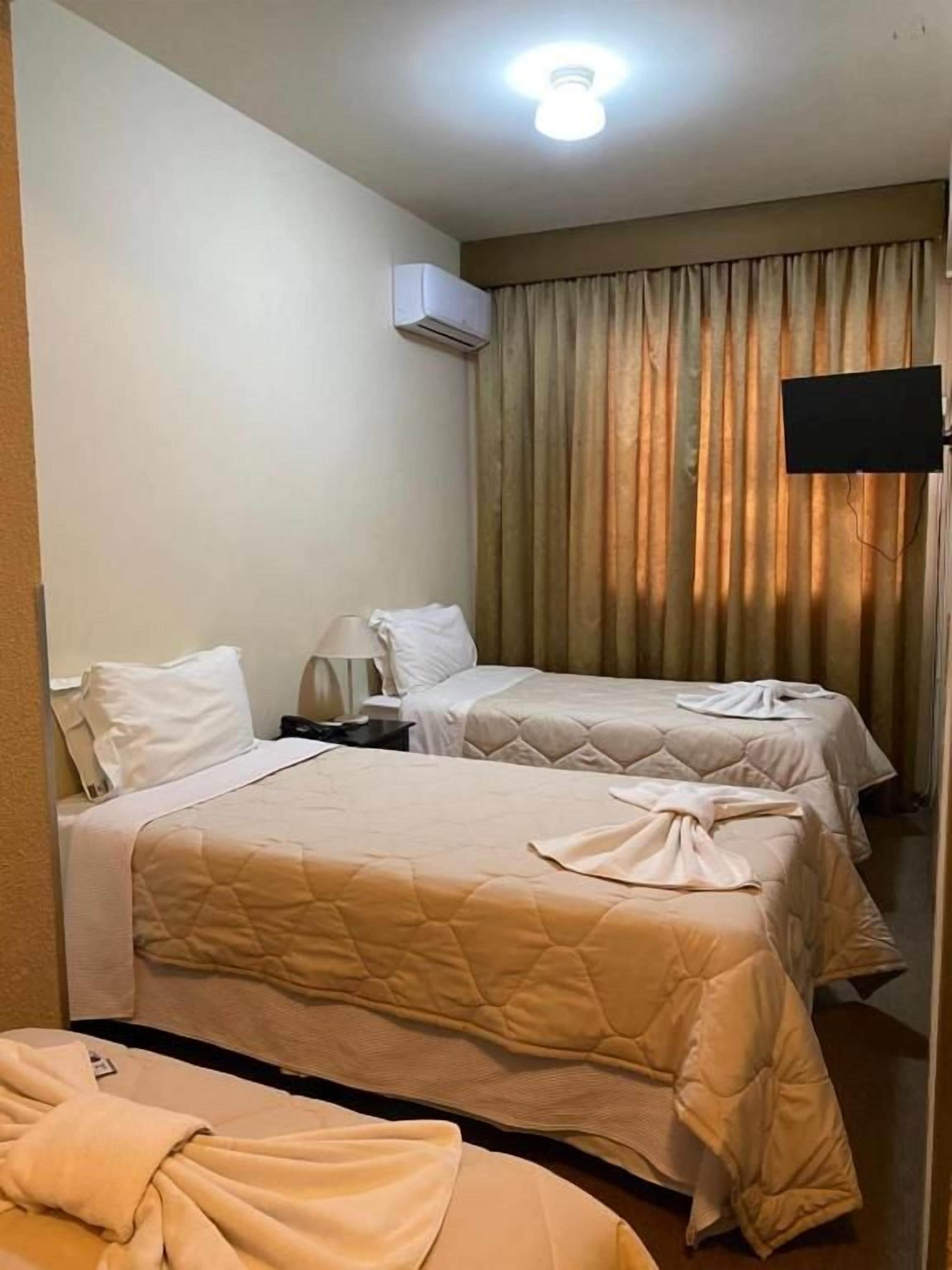 Une chambre d’hôtel avec deux lits, un téléviseur à écran plat et un système de climatisation.
