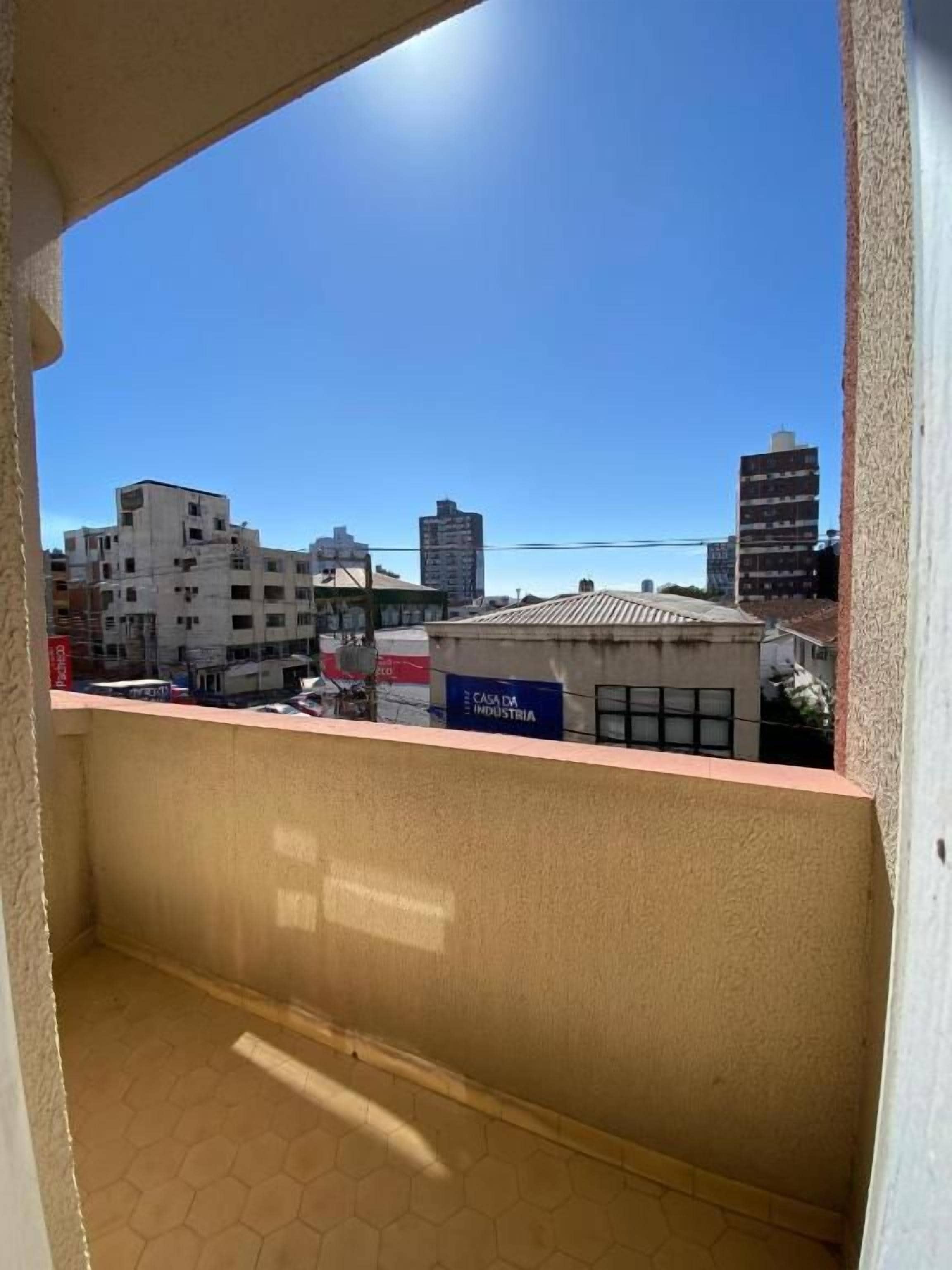 En balkon med udsigt over bybilledet, inklusive bygninger og en klar himmel.
