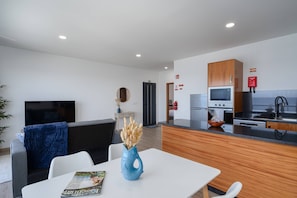 A modern hotel room with a dining area, kitchenette, and a living area with a flat-screen TV. - Casa dos Pescadores by Galmi (Calheta (Madeira))