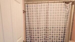 A bathroom with a white door, a shower curtain with a polka dot pattern, a toilet, and a small rug on the floor. - 2-bedroom home great for workforce housing, family, and content creation! (Americus)