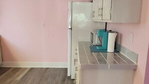 A compact kitchen with a refrigerator, microwave, and a small countertop with a kettle. - 2-bedroom home great for workforce housing, family, and content creation! (Americus)