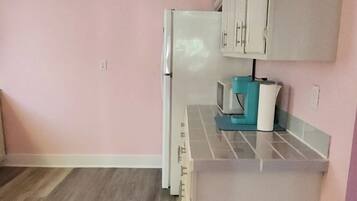A small kitchenette with a refrigerator, microwave, and a coffee maker on the counter.