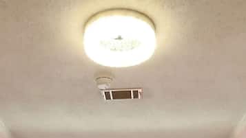 Een kamer met een witte deur, een raam en een plafondlamp.