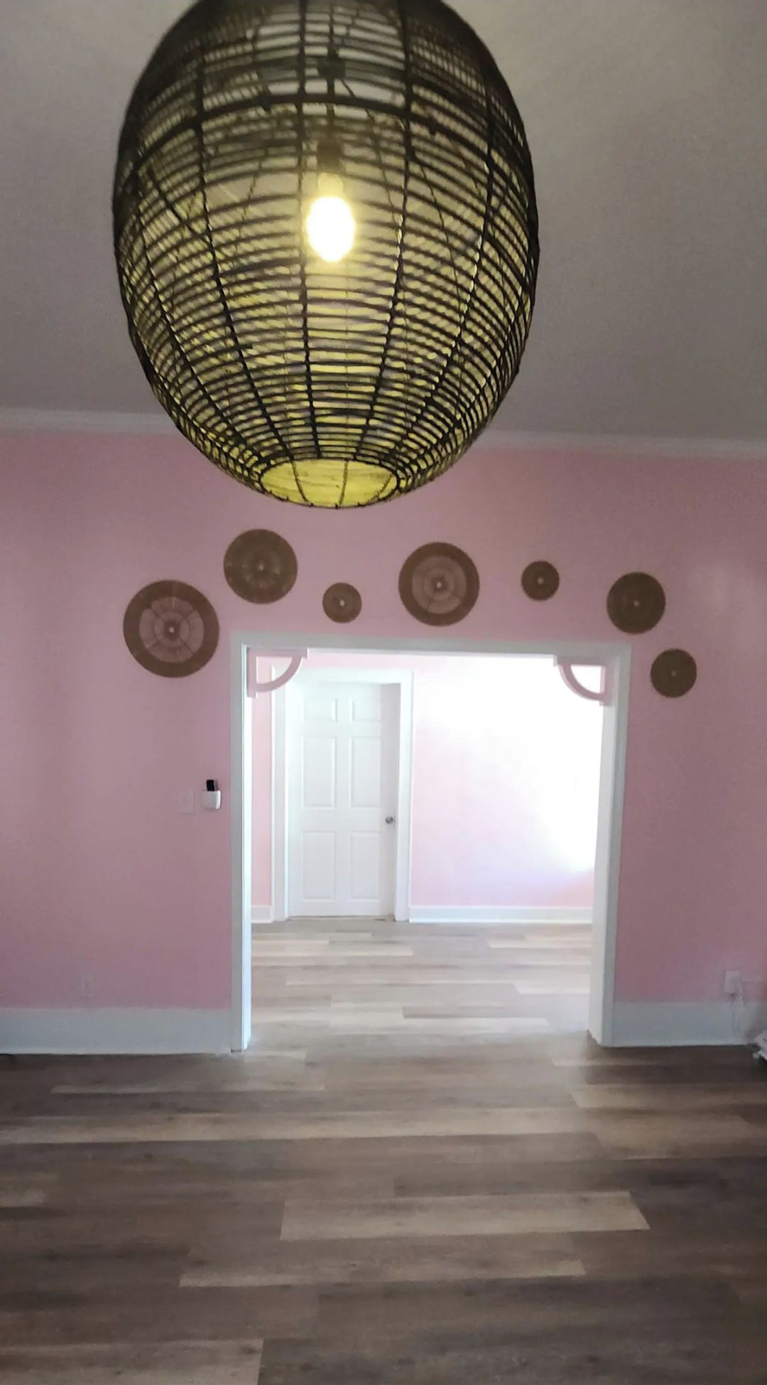 An interior space with a patterned ceiling light, a door leading to another room, and a wall with circular decorations.