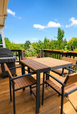 A wooden deck with a table and benches, a grill, and a railing. - Spacious 3BR - 2 Kings, Pool Table + Patios (Centennial)