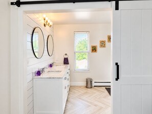 A bathroom with a double sink vanity, a mirror, a towel ring, and a window with blinds. - Spacious 3BR - 2 Kings, Pool Table + Patios (Centennial)