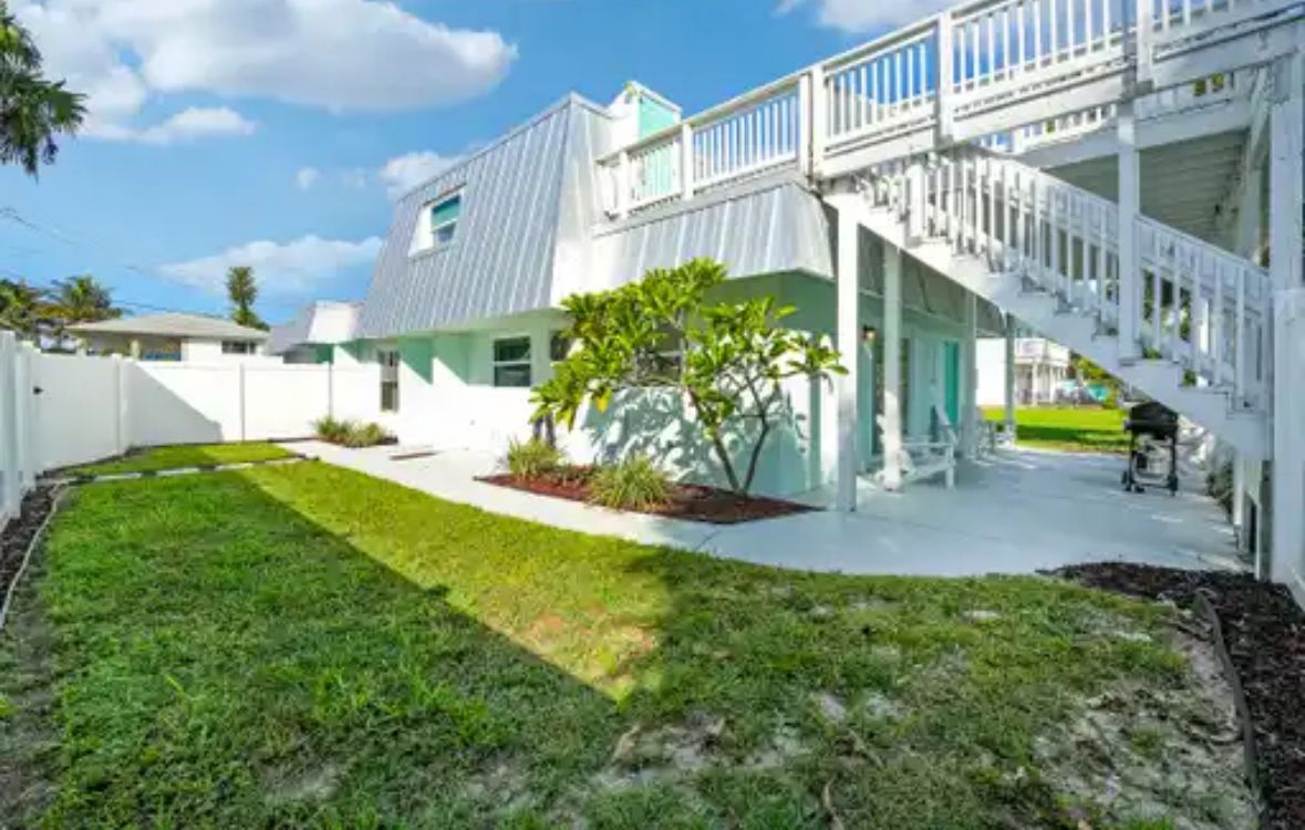 A two-story house with a white exterior, a covered porch, and a staircase leading to the upper level.