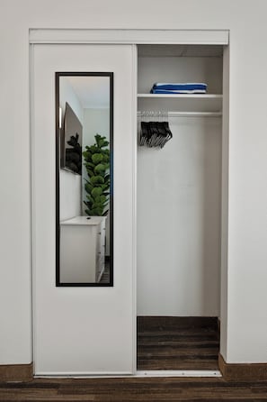 A white door with a mirror, a small plant, and a hanging rack with clothes. - Tranquil 2Bed/2Bath with Balcony Near Universal (Orlando)