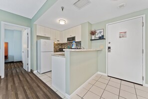 A modern kitchen with white cabinetry, a built-in microwave, and a refrigerator. - Tranquil 2Bed/2Bath with Balcony Near Universal (Orlando)