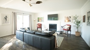 A modern living room with a leather sofa, a fireplace, and a large window with curtains.