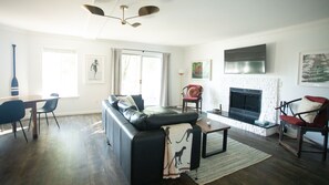 A modern living room with a sectional sofa, a fireplace, and a dining area with chairs.