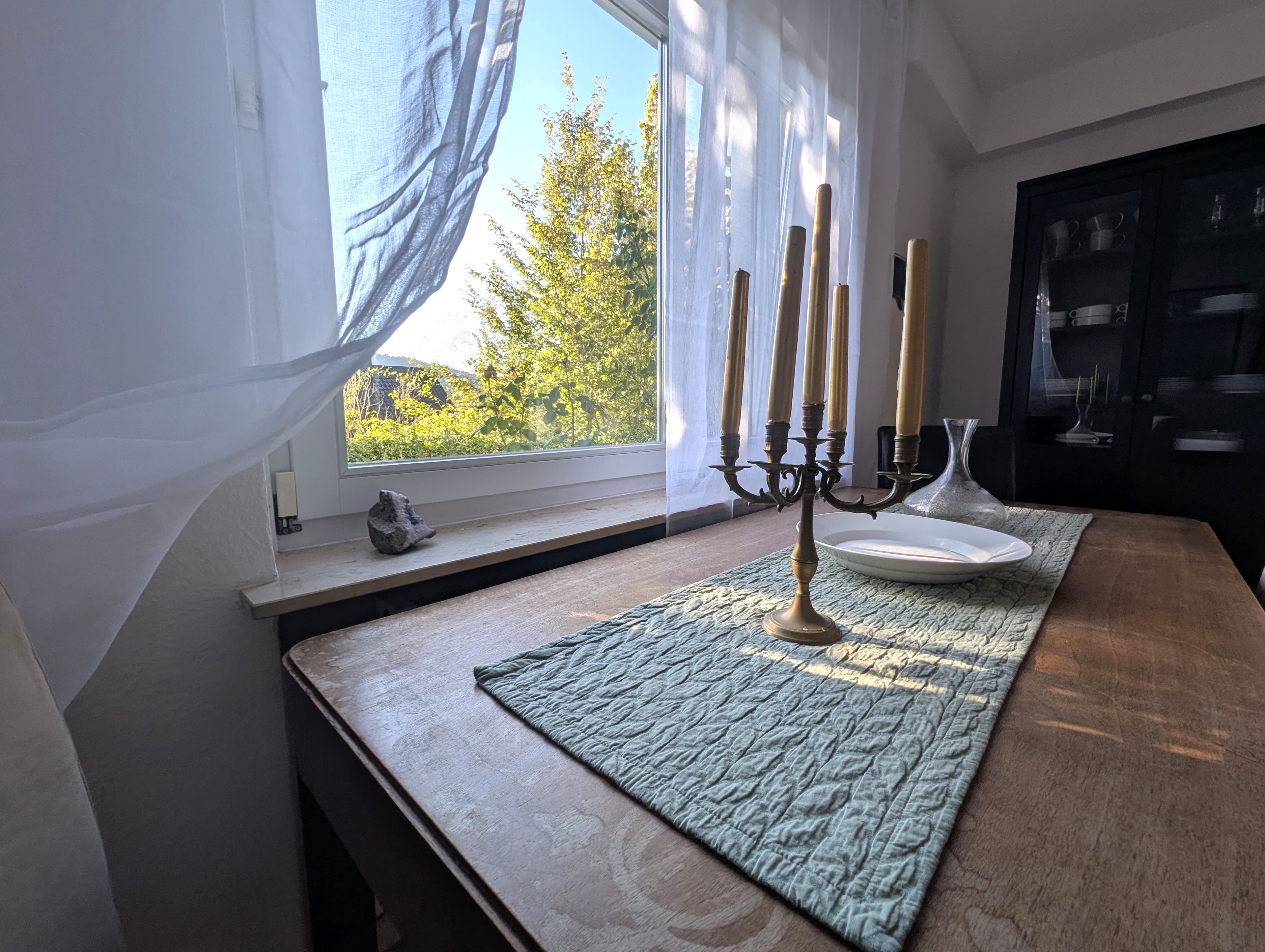 Ein Zimmer mit Fenster, einer Kerzenleuchter, einem Teller und einem Schrank.