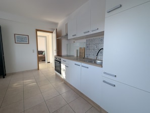A modern kitchen with white cabinets, a stainless steel sink, and a tiled backsplash. - La Maison sur la Colline – Eco-Friendly Getaway with Garden & Scenic Views (Höchst im Odenwald)