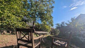 Juego de banco y mesa de madera en un espacio natural al aire libre, con árboles y cielo despejado.