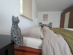 Une chambre à coucher avec un lit, une table de chevet, un bureau, une chaise et une fenêtre.