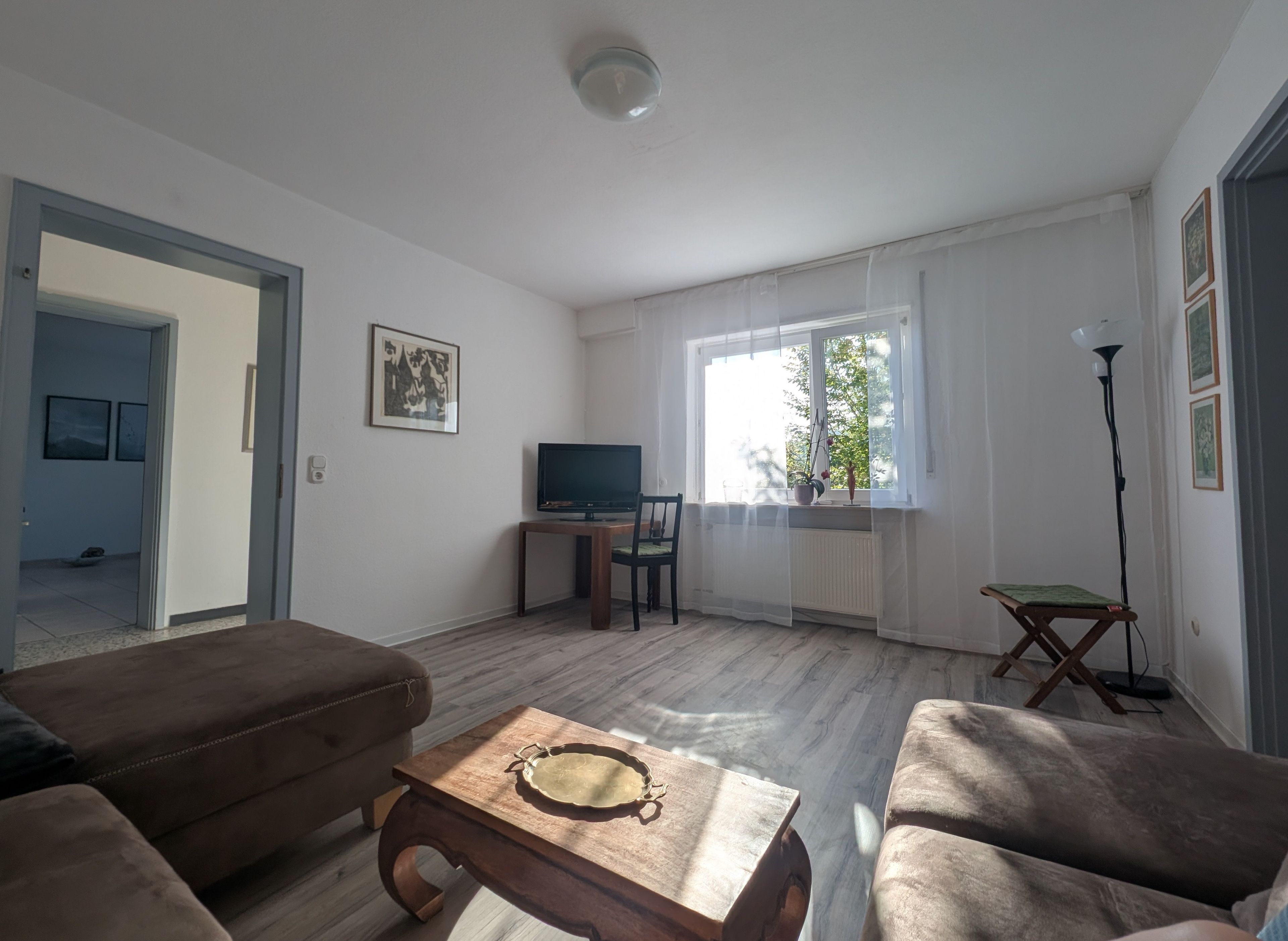 A living room with a sofa, a coffee table, a TV, and a window with curtains.
