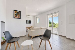 Un salon moderne comprenant un canapé, deux fauteuils, une petite table et un téléviseur.