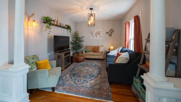 A living room with a television, sofas, a patterned rug, and decorative plants. - Mission House: Historic 4BR Near Downtown (Sioux Falls)
