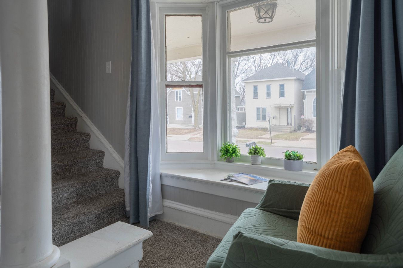 A staircase leading to a landing with a window overlooking a residential street.