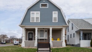 A two-story house with a front porch, a mailbox, and a small window above the door. - Mission House: Historic 4BR Near Downtown (Sioux Falls)