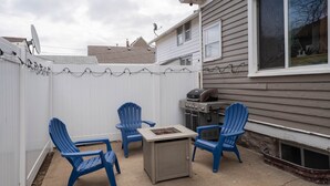 A backyard with a barbecue grill, two blue Adirondack chairs, and a fire pit. - Mission House: Historic 4BR Near Downtown (Sioux Falls)