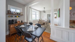 A dining area with a table set for four, a coffee station, and a view into the living room. - Mission House: Historic 4BR Near Downtown (Sioux Falls)