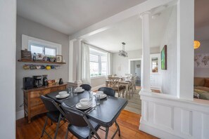 Uma área de refeições com mesa posta para quatro pessoas, um espaço para café e vista para a sala de estar.