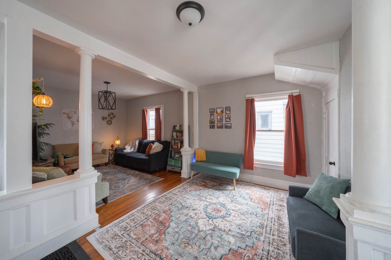 A spacious living room with a large rug, two sofas, a fireplace, and a bookshelf.