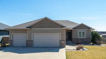 A two-story house with a garage, a stone foundation, and a well-maintained lawn.