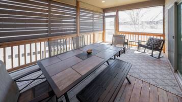 An outdoor patio with a wooden table and chairs, a covered seating area, and a view of a snowy landscape.