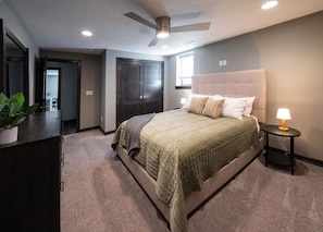 Un dormitorio con cama, mesita de noche y ventilador de techo.