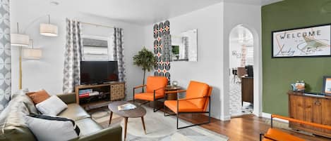 Una sala de estar moderna con un sofá, sillones, una mesa de centro y un televisor.