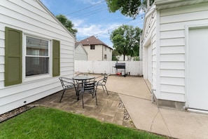 A patio with a table and chairs, a grill, and a white fence. - Lucky Strike: 3 bed, 5 mins to DT, family-friendly (Sioux Falls)