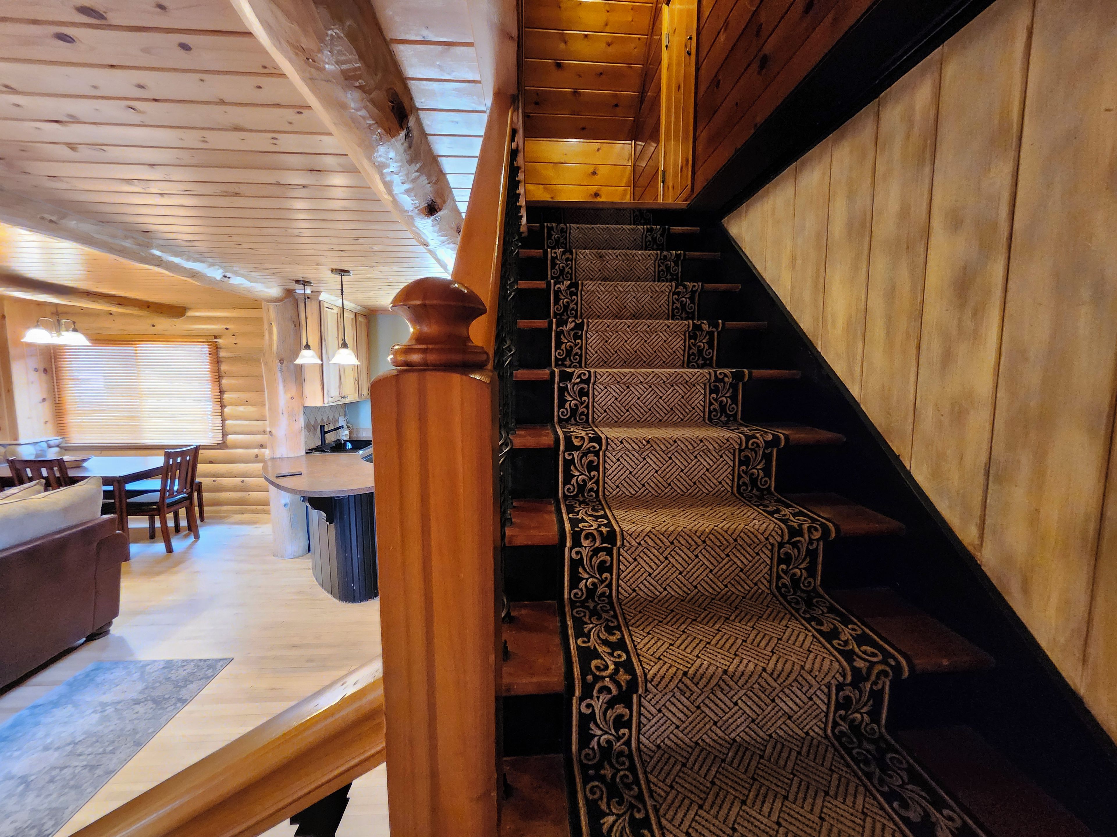 A wooden interior with a staircase, a dining area, and a kitchen.