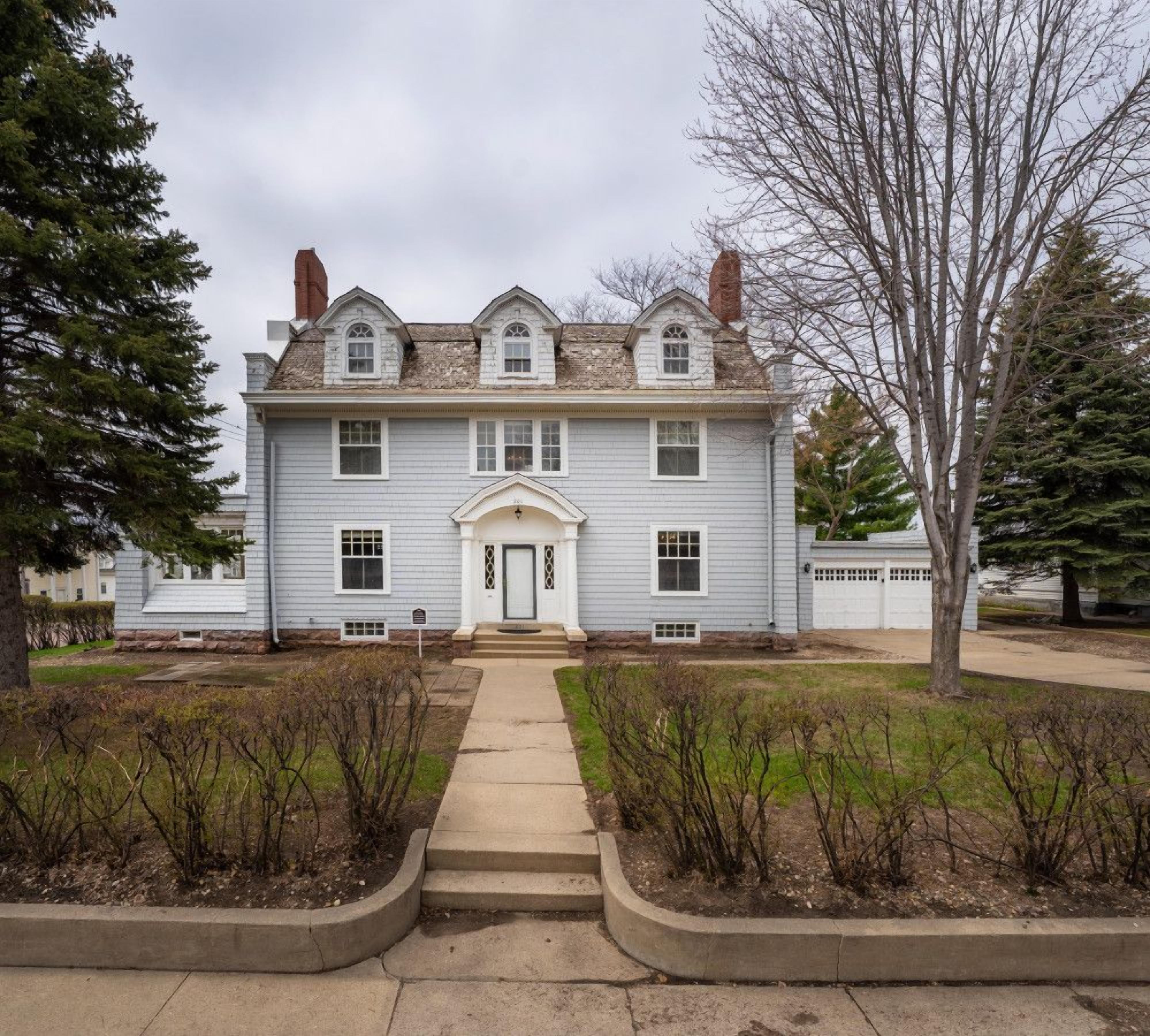 A two-story building with a symmetrical facade, a central entrance with a door, and a small porch area.