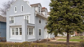 A two-story house with a chimney, a large tree in front, and a well-maintained lawn.