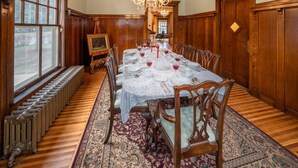 Comedor con una mesa larga dispuesta para seis personas, rodeado de sillas de madera, un candelabro y un ventanal con vistas.