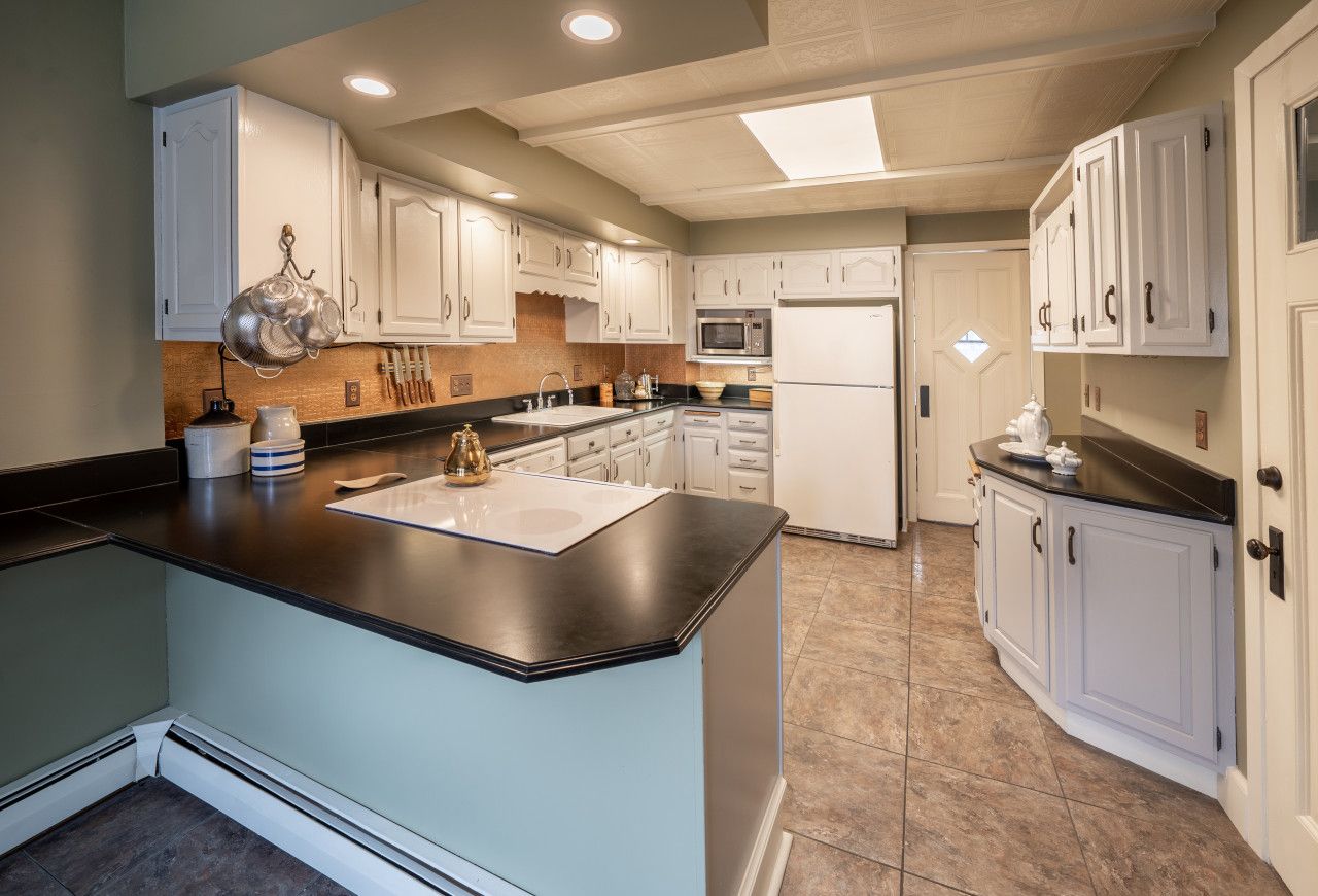 A modern kitchen with white cabinetry, a black countertop, and a central island.