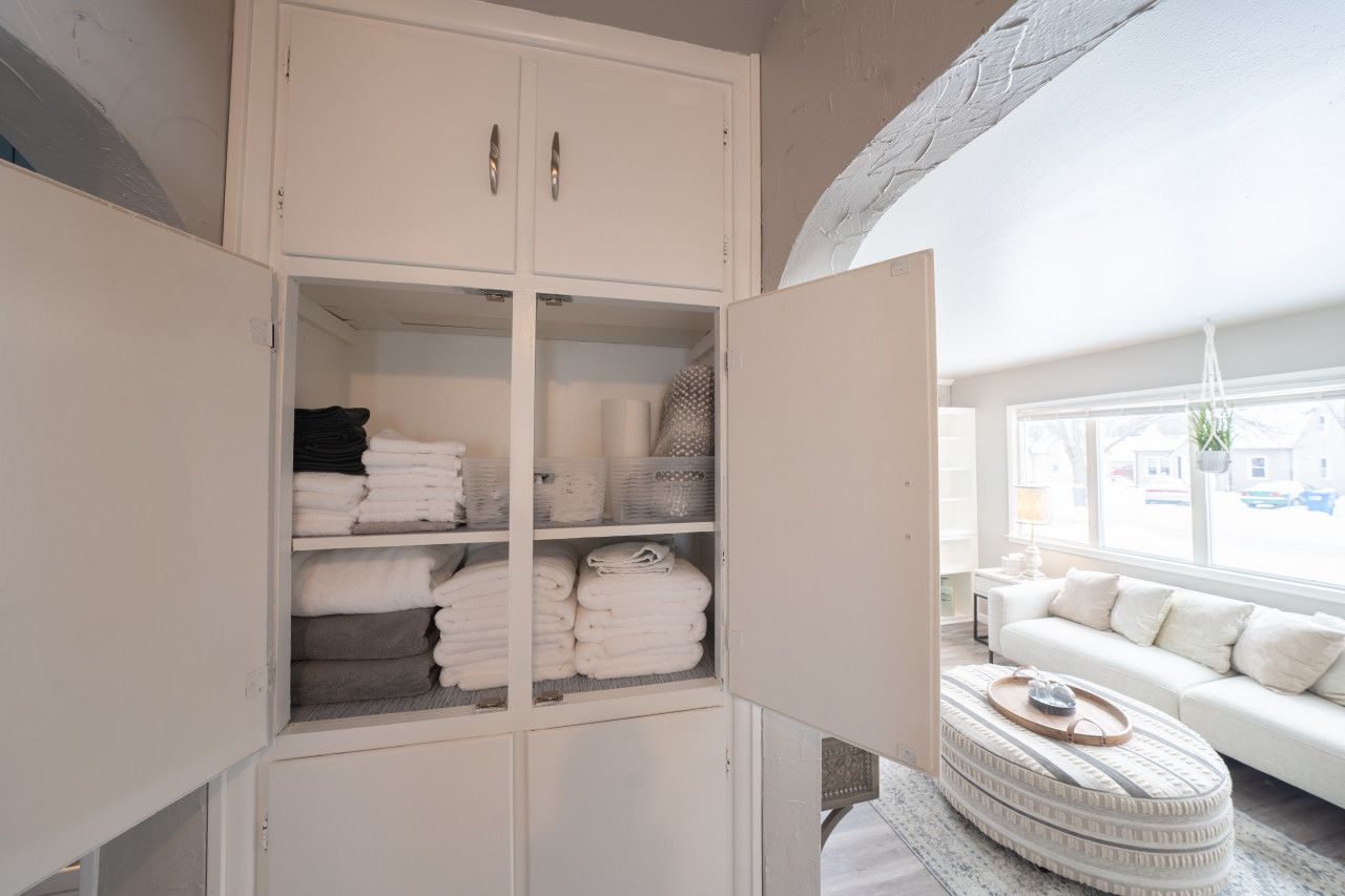 Een kamer met een witte garderobe, een witte bank en een rond voetenbankje met een dienblad.