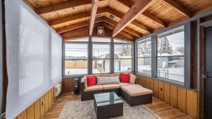 A cozy room with a wooden ceiling, large windows, a sectional sofa, and a glass coffee table. - Duluth Charmer - 3B/2B cozy home (Sioux Falls)