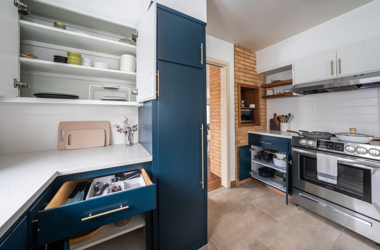 Una cocina moderna con armarios blancos, un mueble azul y electrodomésticos de acero inoxidable.