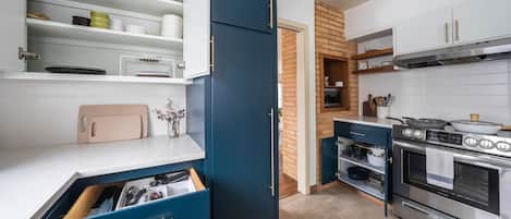 A modern kitchen with white cabinets, a blue cabinet, and stainless steel appliances.