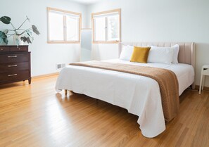 Ein Schlafzimmer mit einem Bett, einem Schminktisch und zwei Fenstern.