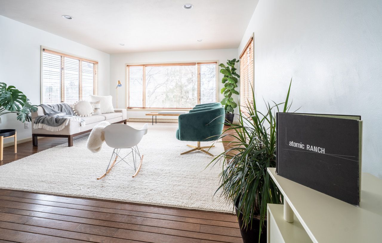 Una sala moderna con sofá, sillones, una mesa de centro y un ventanal grande.