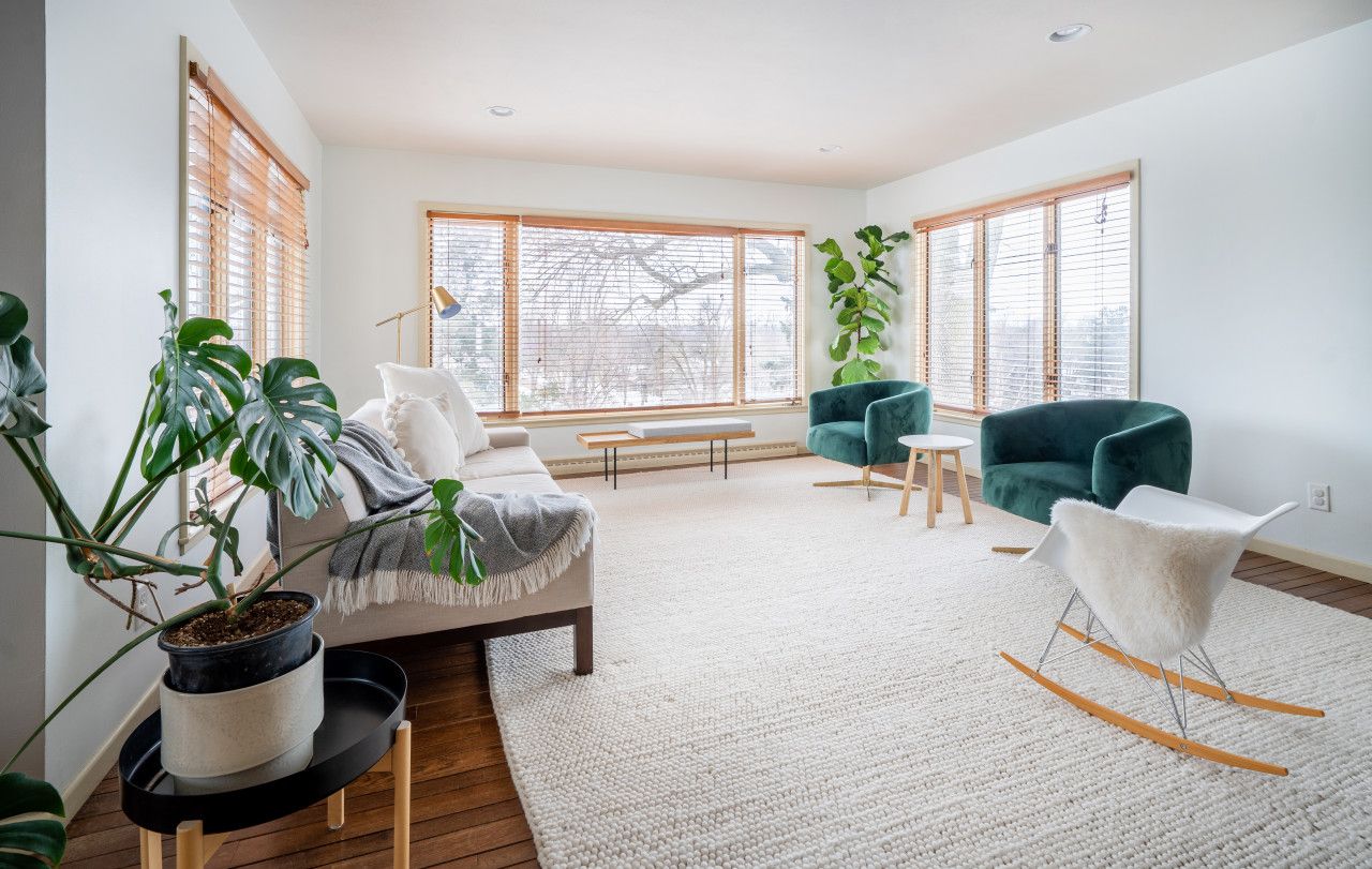 A modern living room with a sofa, chairs, a coffee table, and large windows.