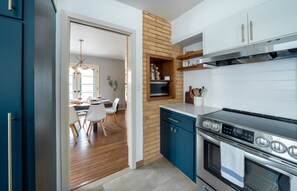 Een moderne keuken met een accentmuur van baksteen, een ingebouwde magnetron en een roestvrijstalen afzuigkap.