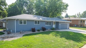 A single-story house with a garage, a well-maintained lawn, and a driveway. - Dakota Haven: Family-Friendly, Clean, Sleeps 8 (Sioux Falls)