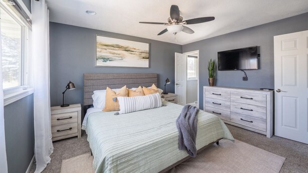 A bedroom with a bed, bedside tables, a ceiling fan, a TV, and a dresser. - Dakota Haven: Family-Friendly, Clean, Sleeps 8 (Sioux Falls)